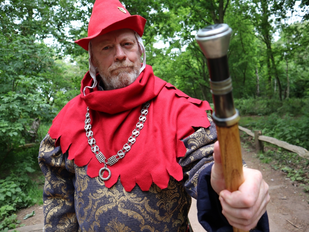 The Sheriff of Nottingham stands at the entrance to Sherwood Forest, pointing his cane.