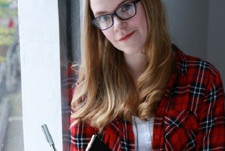 Author Sarah Juckes sitting with a book and a pen
