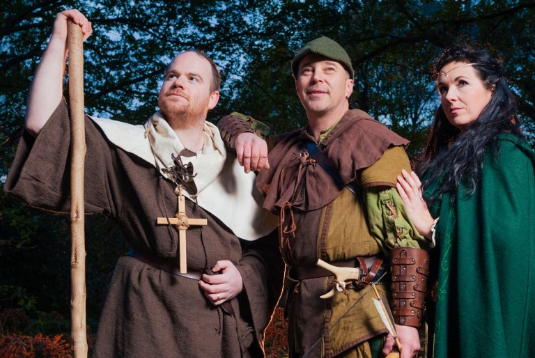 Friar Tuck, Robin Hood and Maid Marian look into the distance at Sherwood Forest.